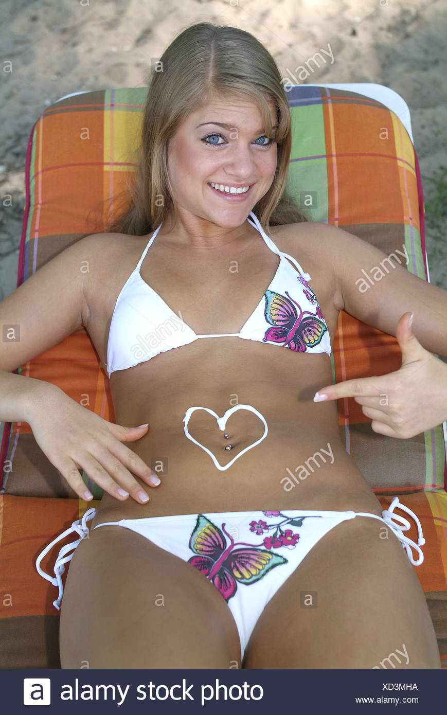 Eine Blonde Frau Im Bikini Zeigt Das Herz Auf Dem Bauch Gemalt Als Sie Auf Der Liege Sitzt Stockfotografie Alamy
