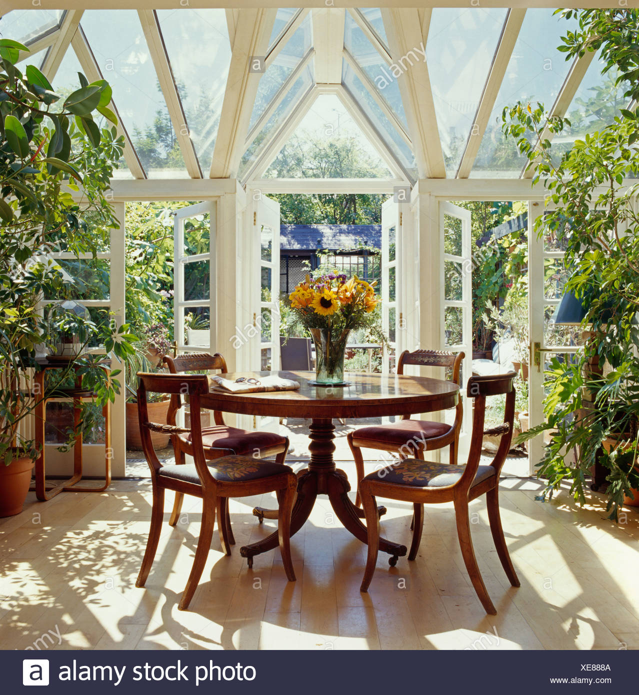 Antiker Runder Tisch Und Antike Stuhle Im Sonnigen Wintergarten Mit Turen Offnen Sich Zum Garten Stockfotografie Alamy