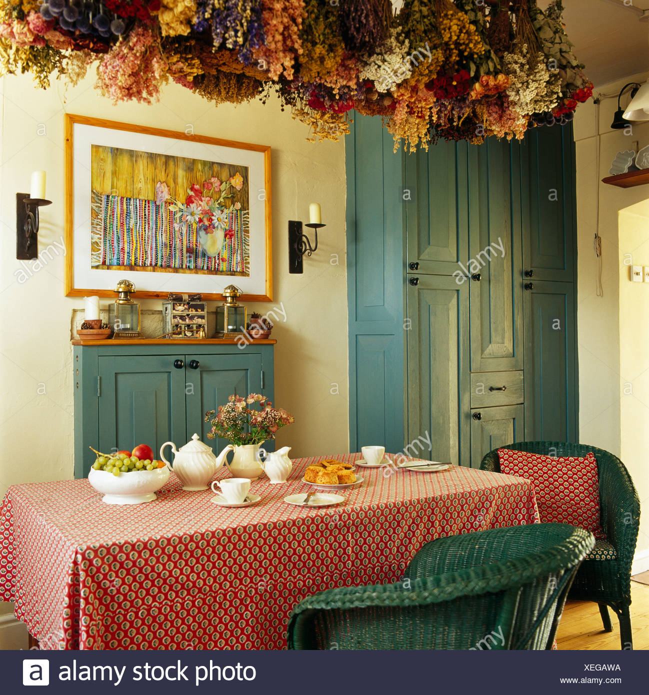 Getrocknete Blumen Auf Der Decke Uber Dem Tisch Mit Rosa Stoff In Traditionellen Speisesaal Mit Bild An Die Wand Gemalten Blauen Schrank Stockfotografie Alamy