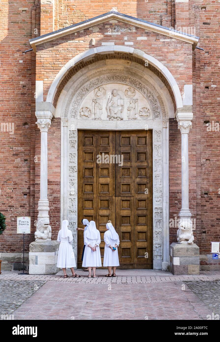 Las monjas contemplan la Porta Santa de la Iglesia de la Abadía de San Silvestro, románico, Nonantola, provincia de Módena, Emilia-Romaña, Italia Foto de stock