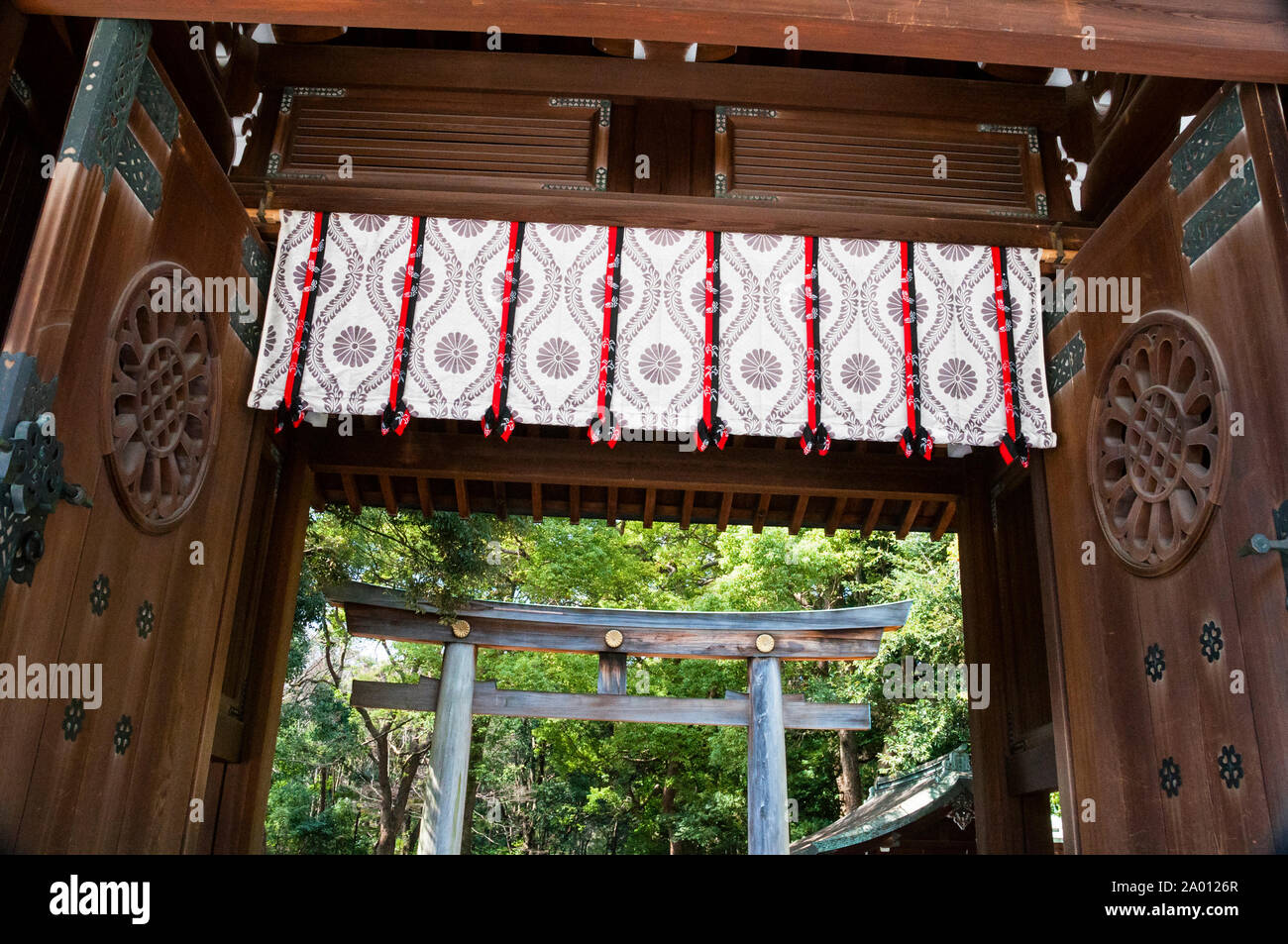 Las enormes puertas y el ciprés torii de 40 pies de altura son una entrada dominante al santuario Meiji Shinto, el santuario sintoísta más famoso de Tokio. Foto de stock