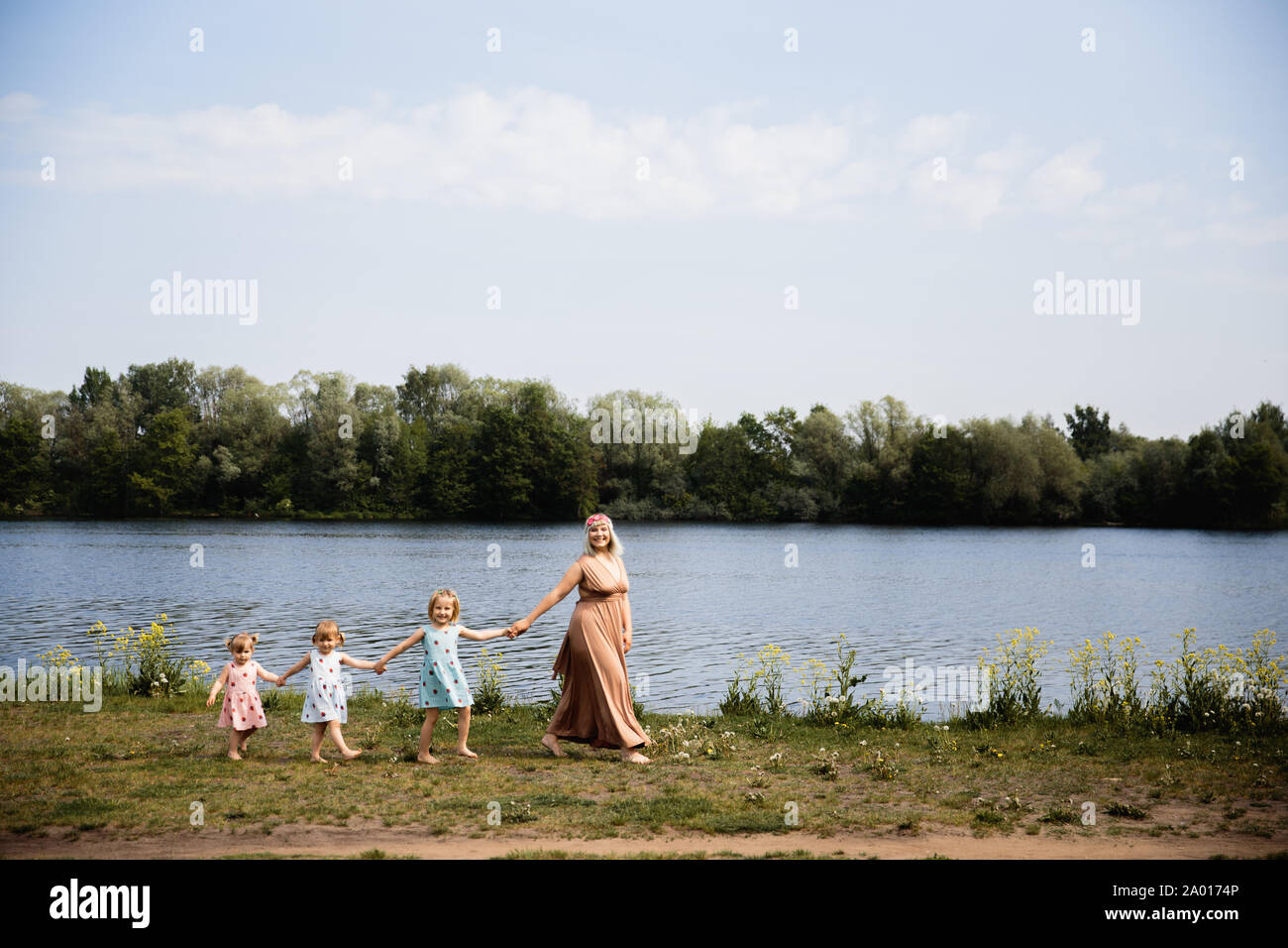 Madre hubiera divertido jugando tiempo de calidad con su bebé a las niñas en un parque soplando jaramago - joven rubia hippie - hijas con vestidos similares de desgaste Foto de stock