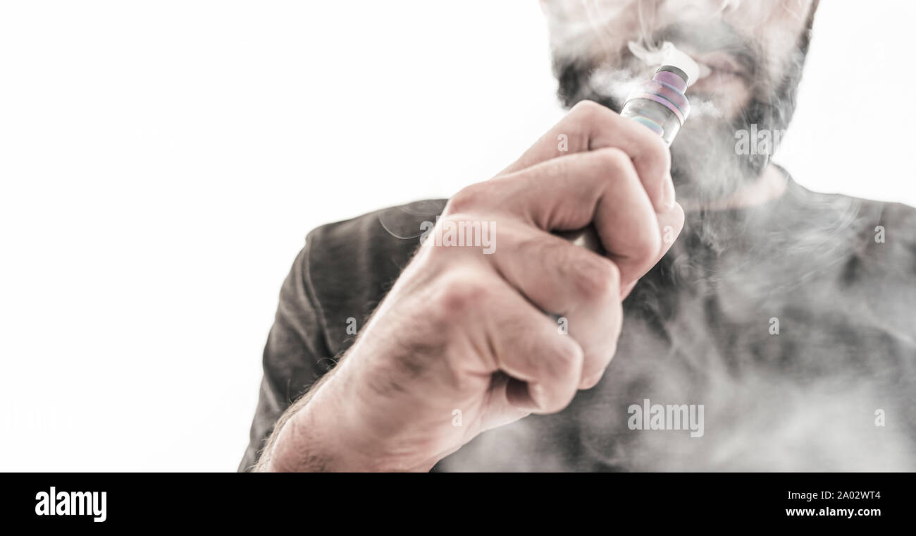 Adulto hombre caucásico con barba vaping e-cigarrillo como alternativa de tabaco contra el fondo blanco. Foto de stock