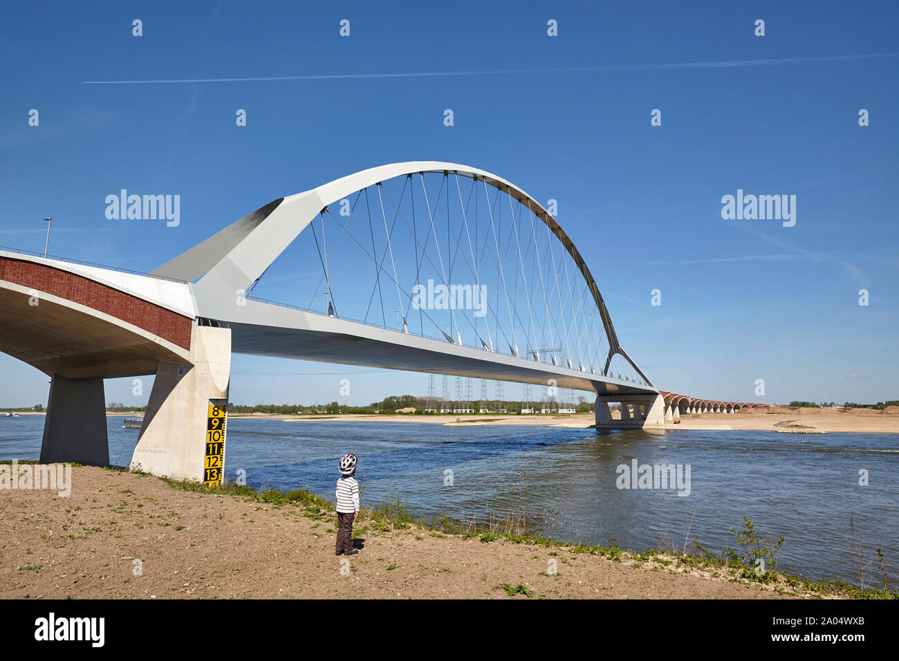 Joven con casco mirar el puente denominado De oversteek, que cruza el río Waal en Nimega Foto de stock