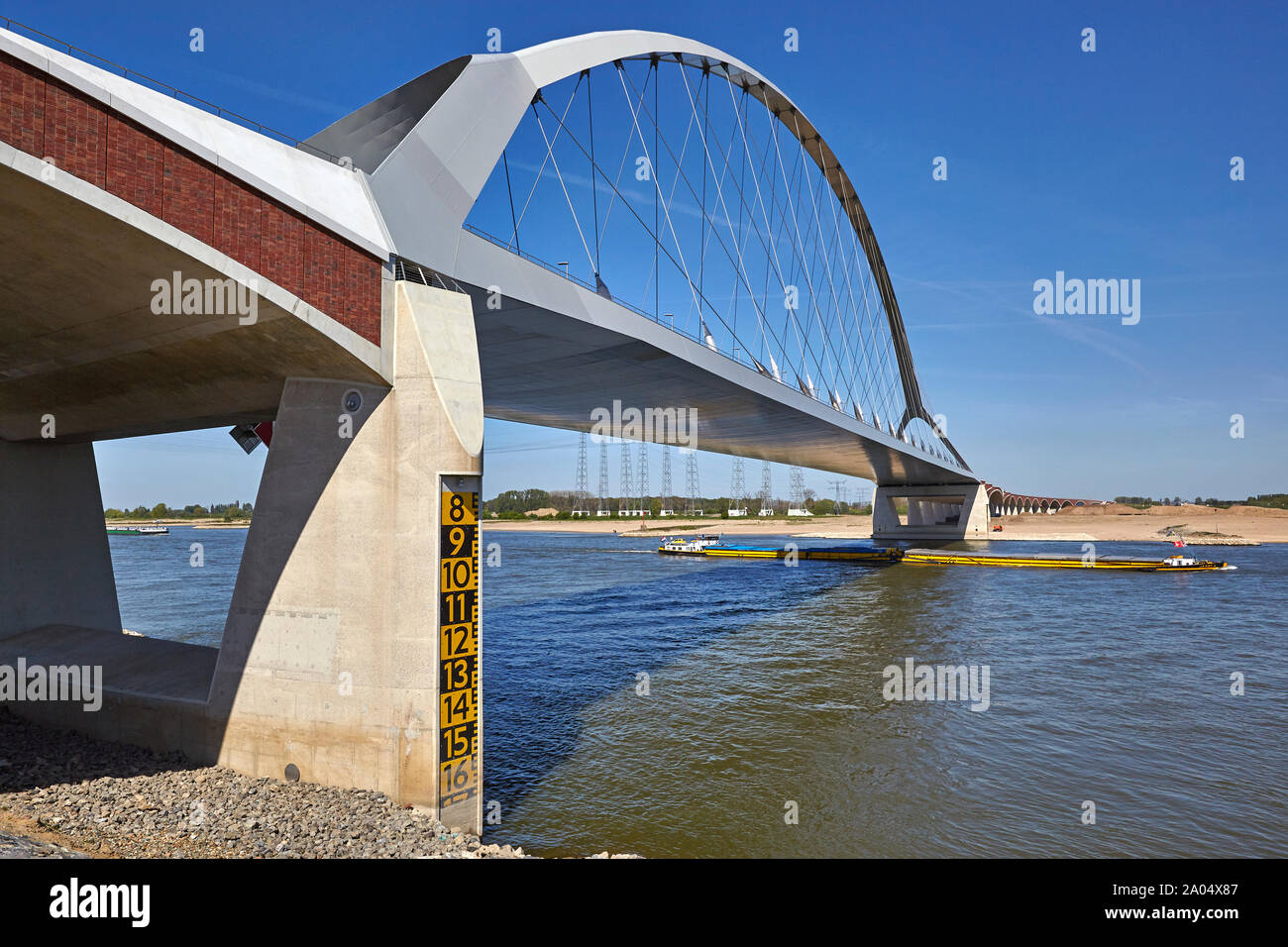 Barcazas navegando bajo la Oversteek puente que cruza el río Waal en Nimega en Holanda Foto de stock