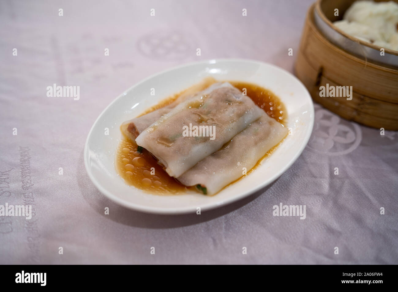 Carne estilo Hong Kong fideos de arroz rollos (Cheung fun) sobre una placa blanca en una mesa de restaurante Foto de stock
