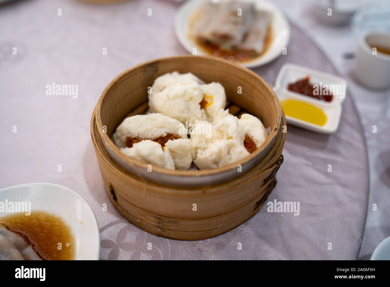 Cocer la carne de cerdo a la barbacoa estilo Hong Kong bollos en una canasta de bambú en una mesa de restaurante Foto de stock