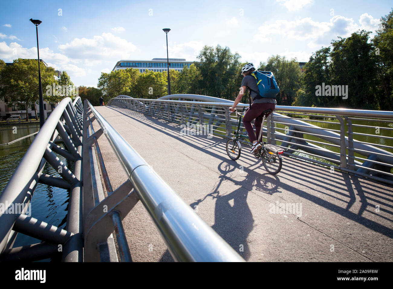 Hombre en bicicleta plegable en el puente en el Mediapark, en Colonia, Alemania. Mann auf Klapprad auf der Bruecke im Mediapark, Koeln, Deutschland. Foto de stock