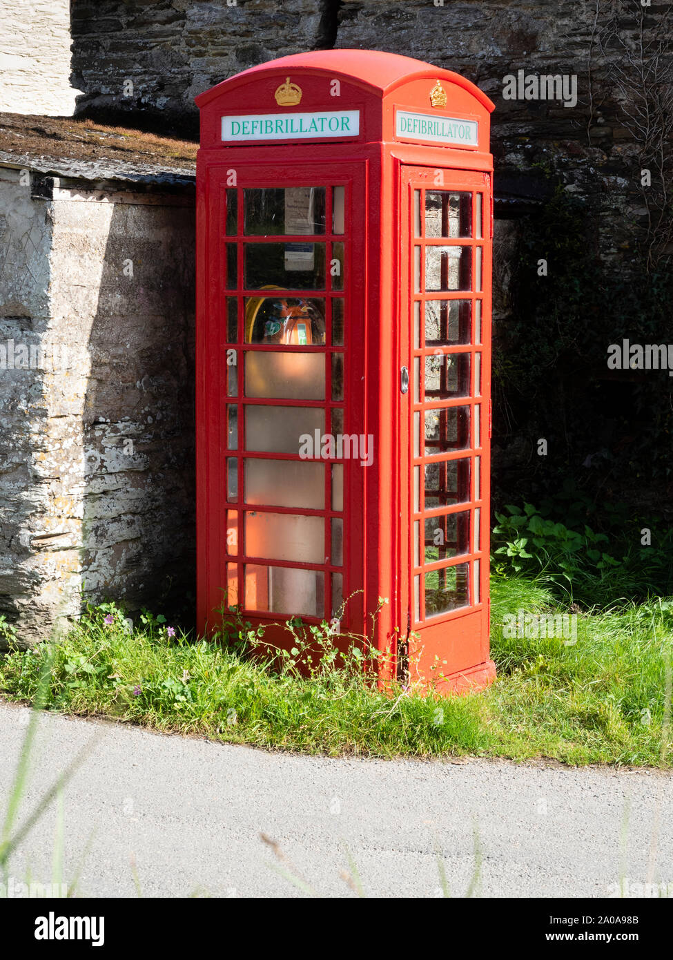 BT obsoletos icónico cuadro Teléfono rojo rediseñarse para albergar un desfibrilador en un carril de Devon Foto de stock