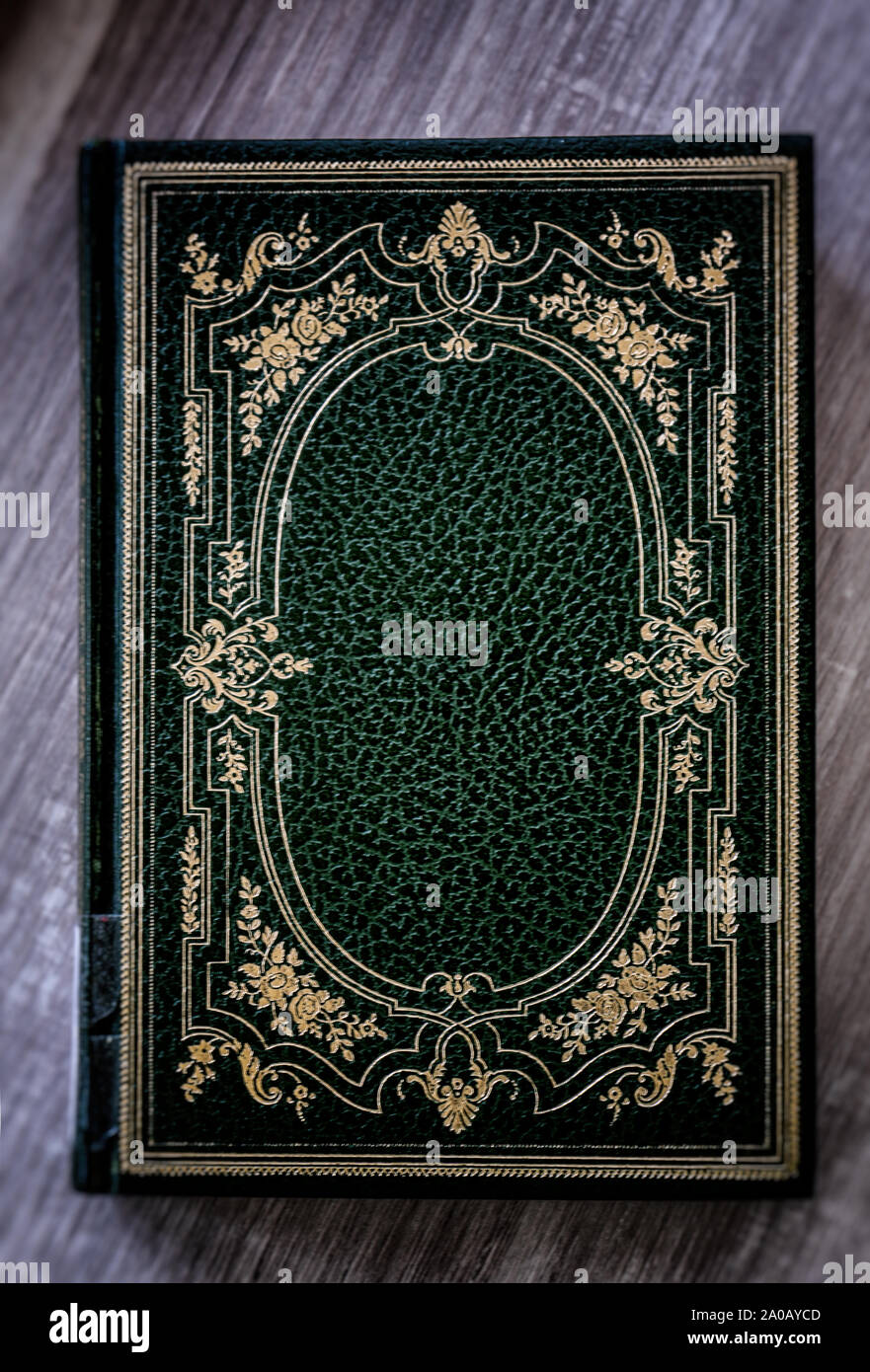 Un libro antiguo con cubierta verde con decoraciones doradas descansando  sobre la mesa de madera Fotografía de stock - Alamy