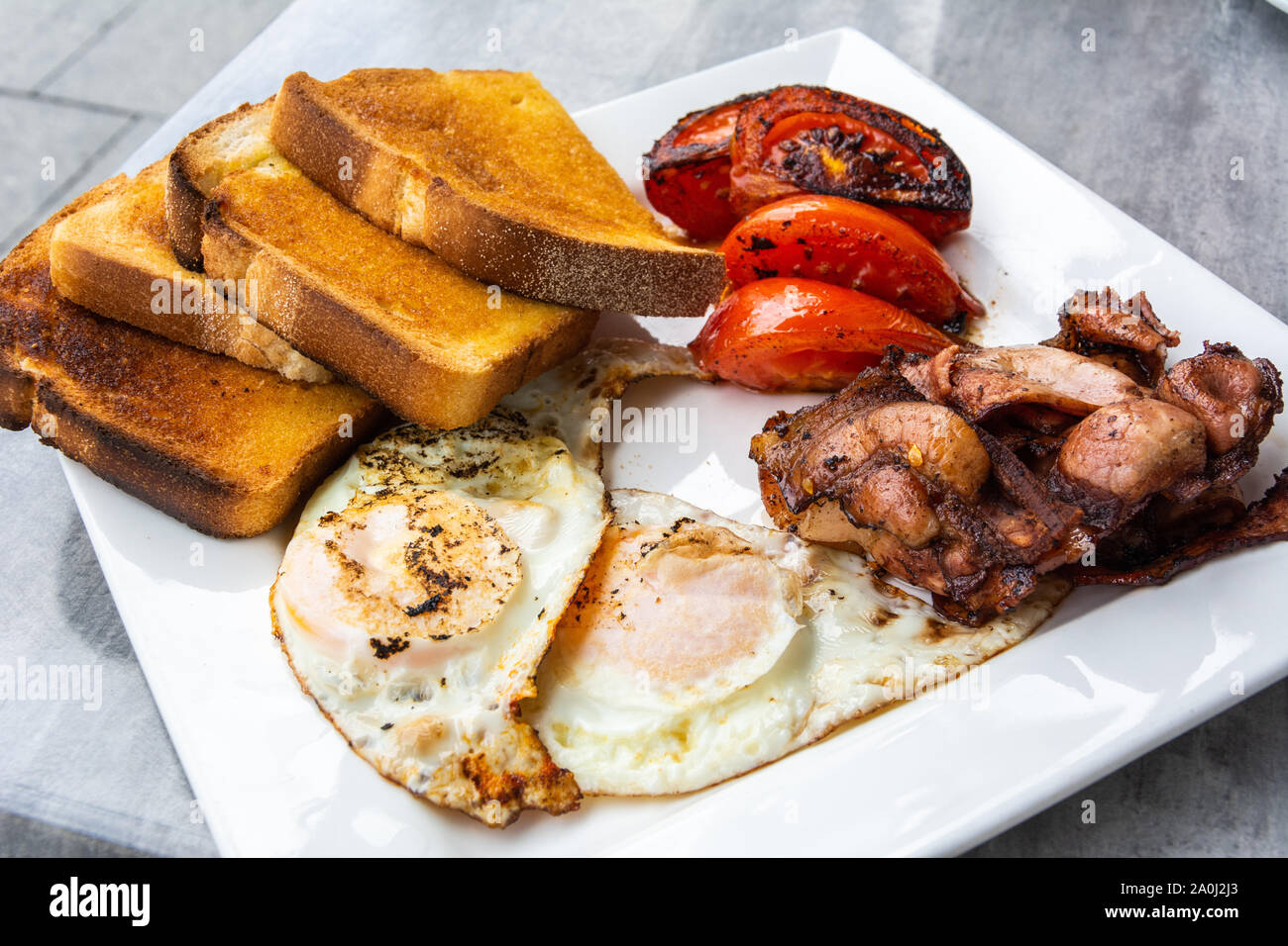 Desayuno australiano con huevos fritos, tocino, tomate y las tostadas. Foto de stock