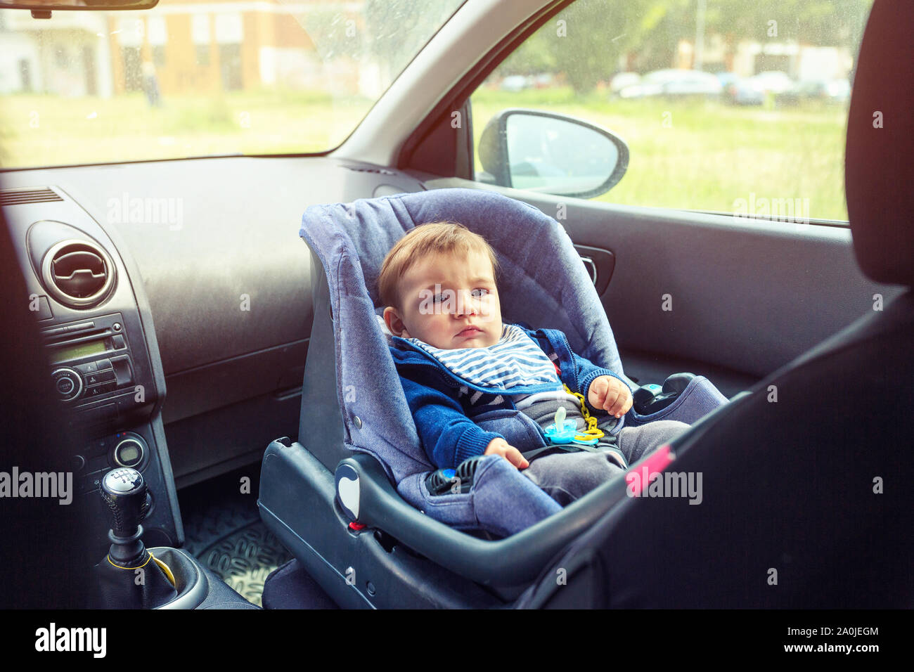 Asiento de bebé para el coche de seguridad. Baby Boy sonriente sentado en una silla de coche de seguridad. Protección en el coche. Foto de stock