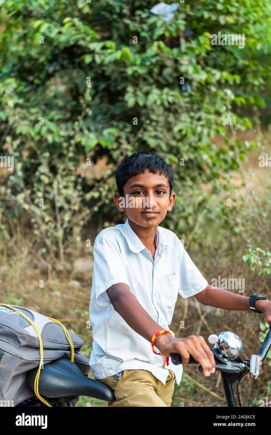 PUTTAPARTHI, INDIA - Noviembre 29, 2018: niño indio sobre una bicicleta. Vertical. Con el enfoque selectivo Foto de stock