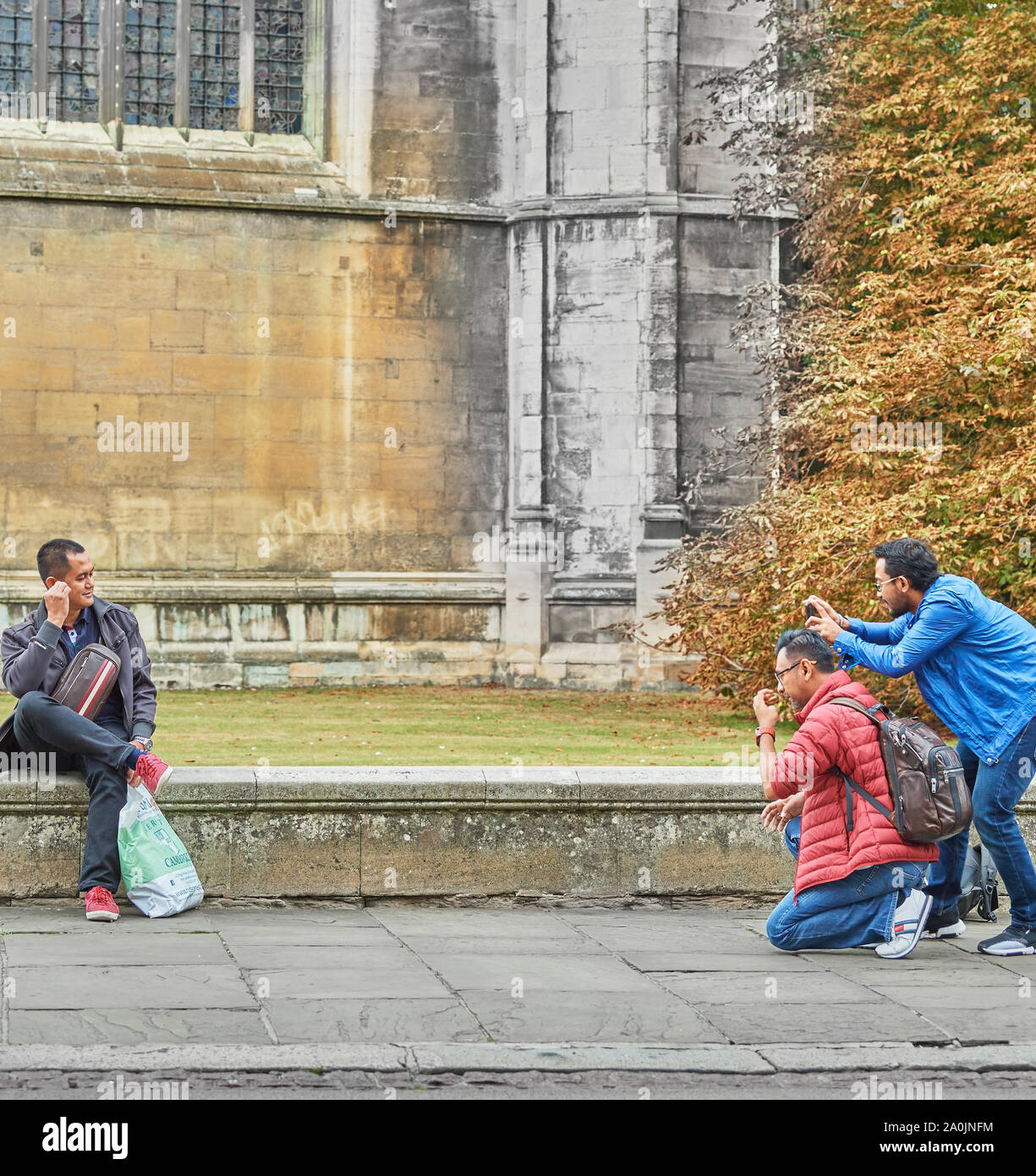 Los turistas tomar una foto en la pared baja fuera de la capilla de King's College, Universidad de Cambridge, Inglaterra. Foto de stock