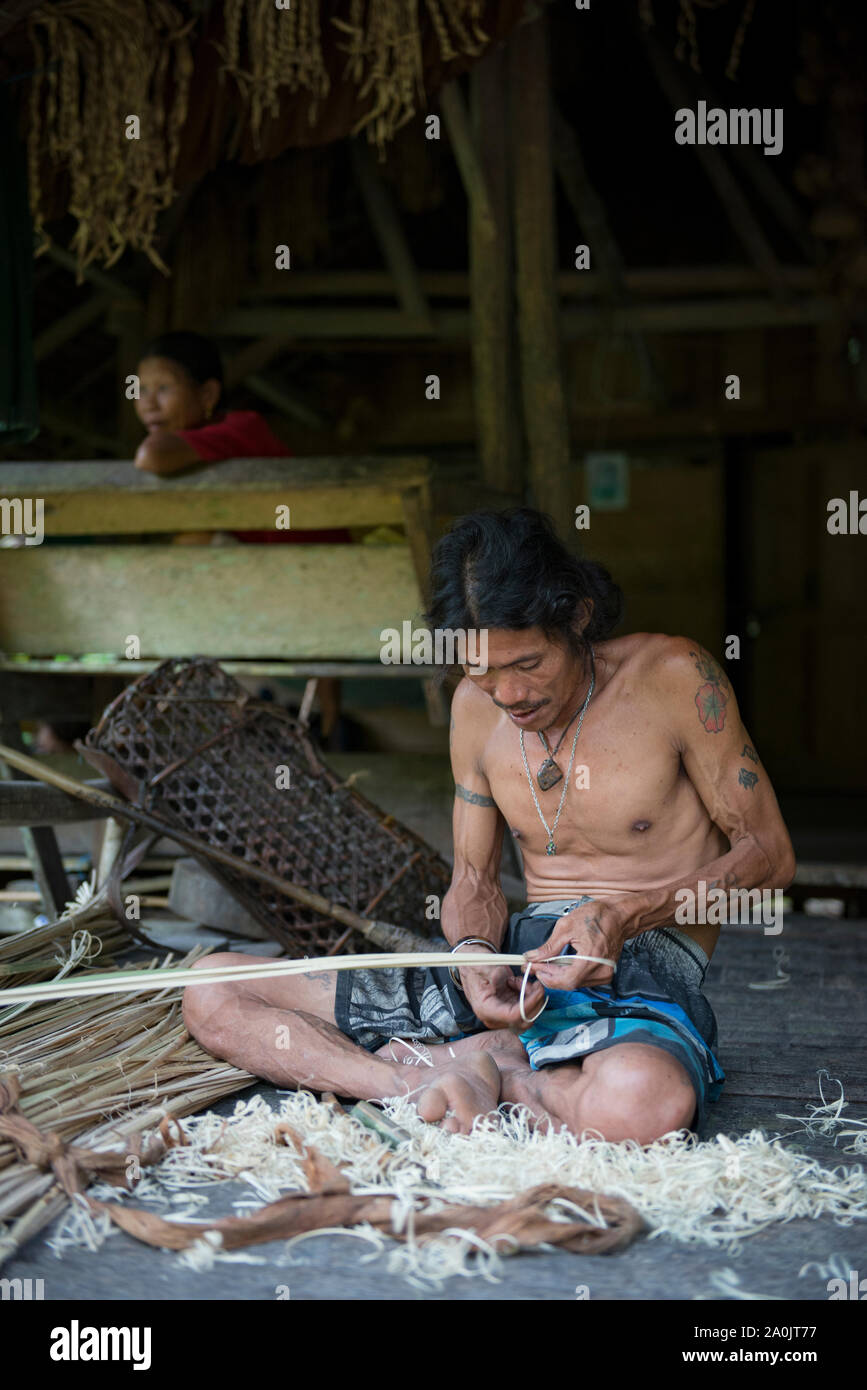 Hombre de la tribu Mentawai realizando artesanía en madera Foto de stock