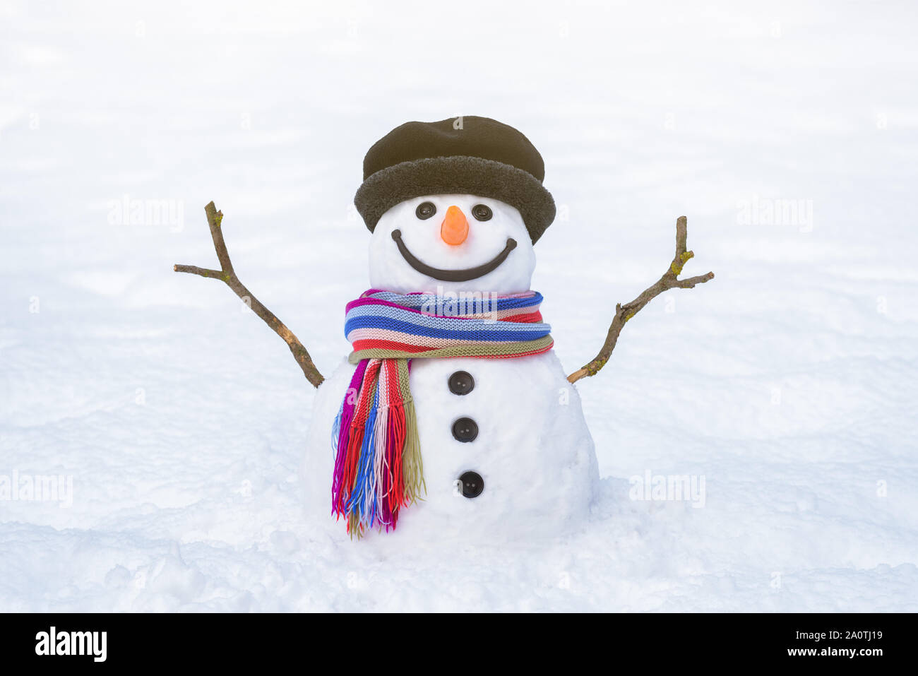 Tarjeta de navidad. Gracioso muñeco de nieve con una bufanda de rayas brillante sobre un fondo blanco de nieve Foto de stock