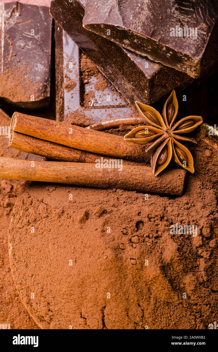 Recipiente con el polvo de cacao y trozos de chocolate oscuro en el fondo marrón Foto de stock