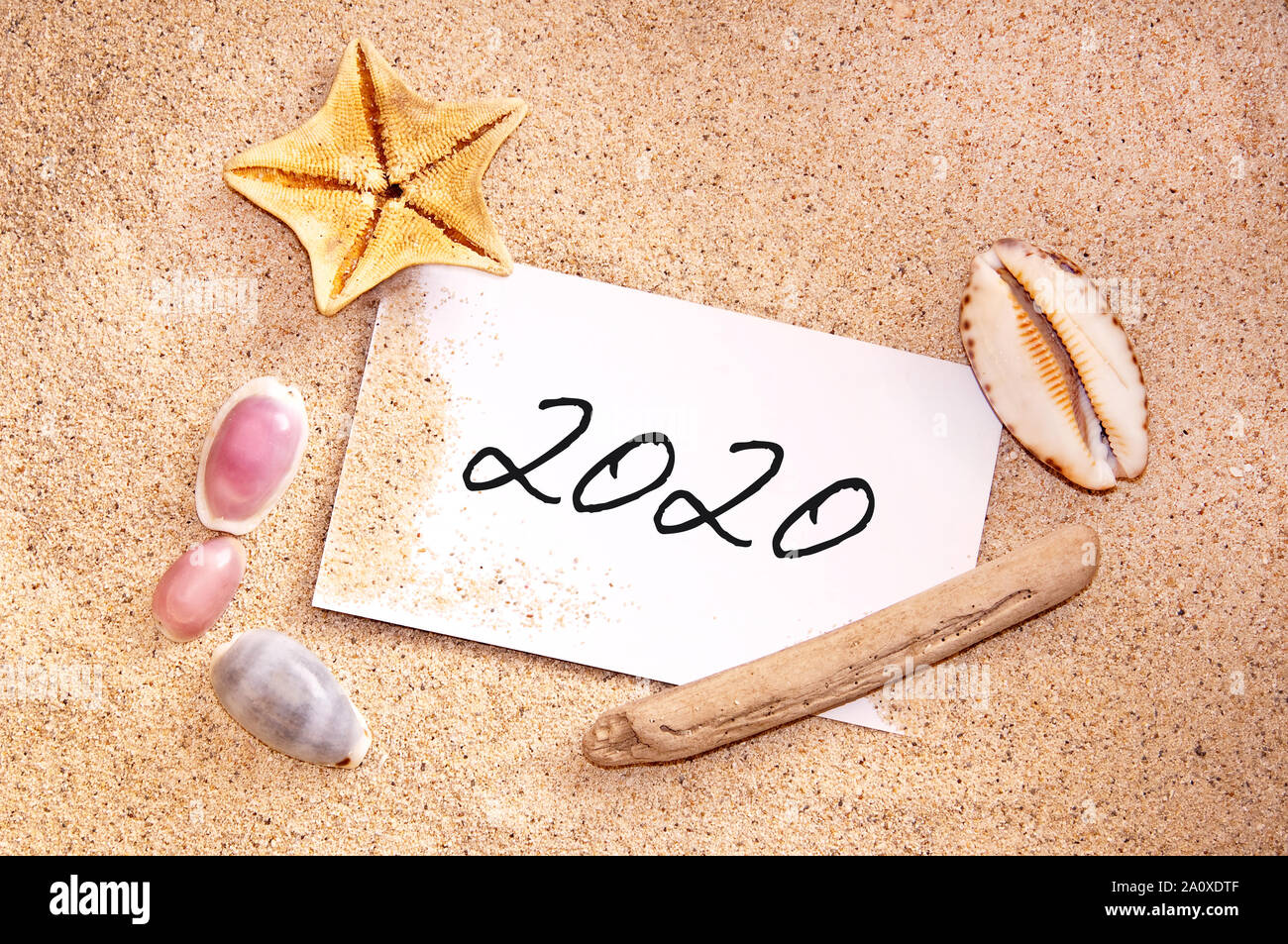 2020 en una nota escrita en la arena de una playa tropical de conchas, vacaciones, vacaciones de año nuevo card Foto de stock