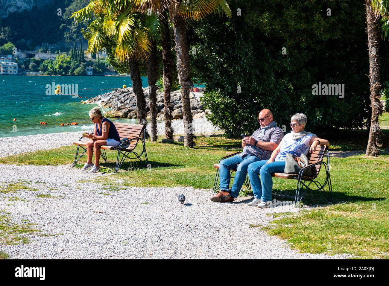 Los turistas en teléfonos móviles, por el lago, Riva del Garda Trentino, Alto Adige, en el norte de Italia Foto de stock