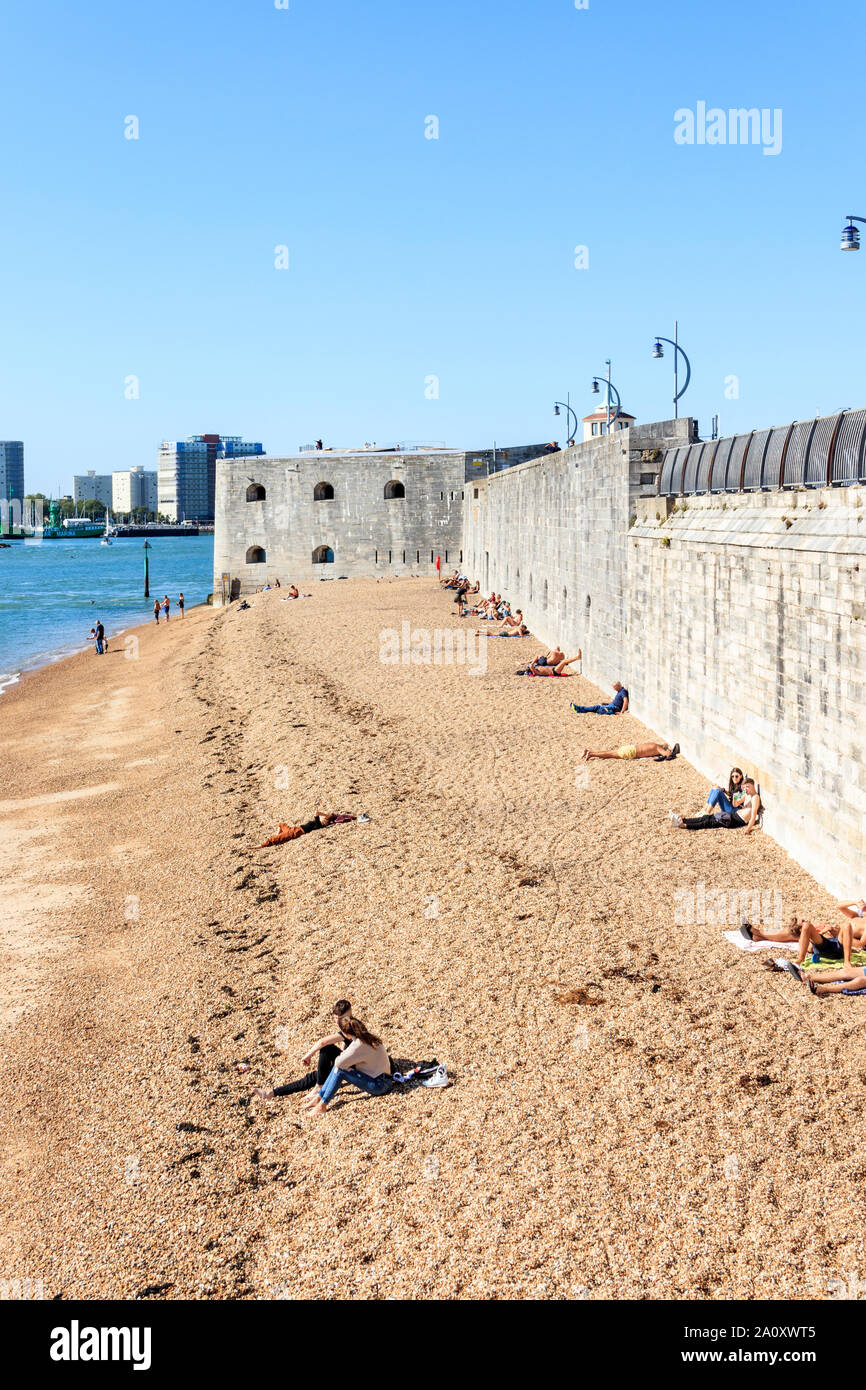 Las personas tomando sol en la playa en el puerto de Portsmouth, la Torre Redonda en el fondo, Portsmouth, Reino Unido Foto de stock