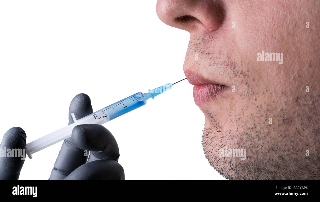 Inyectar botox en un joven caucásico labios del hombre. Jeringa con líquido  azul y una aguja en una mano con guante protector negro. Aislado en blanco  backgr Fotografía de stock - Alamy