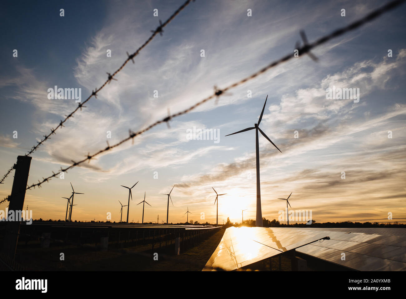 Alambre de púas, turbinas de viento y paneles solares en un campo en Alemania Foto de stock