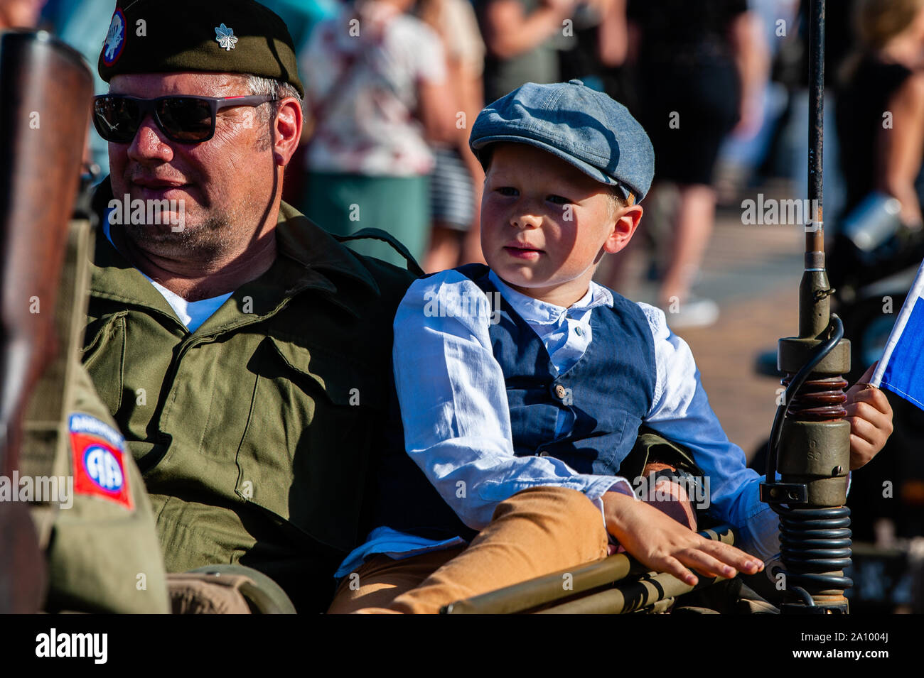 Un hombre vestido con ropa militar llevando un chico durante el  desfile.vehículo militar desfile conmemorativo de los 75 años desde que  tuvo lugar la operación Market Garden. La operación Market Garden fue