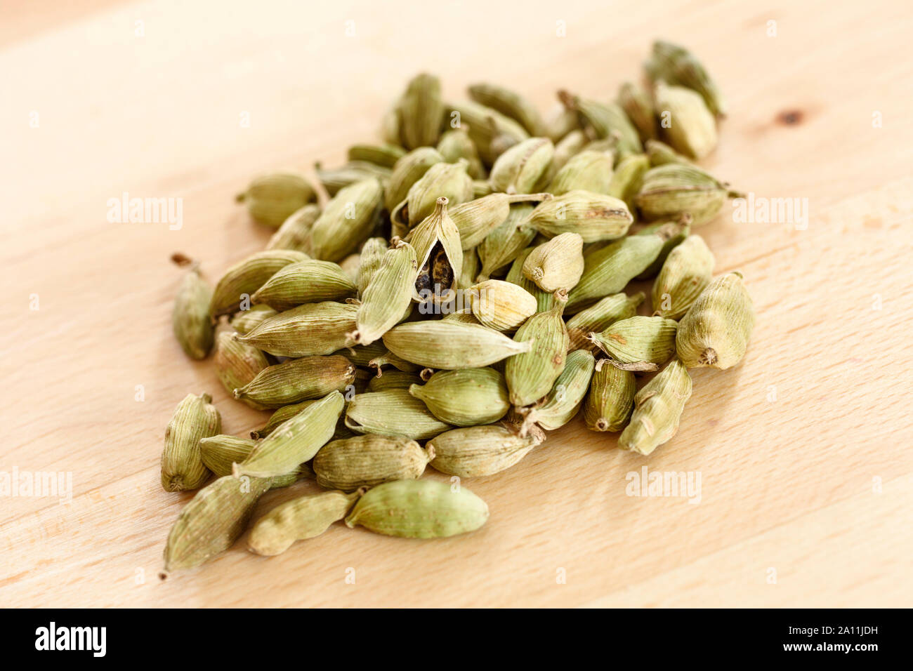 Las semillas de cardamomo en un montón sobre una superficie de madera Foto de stock