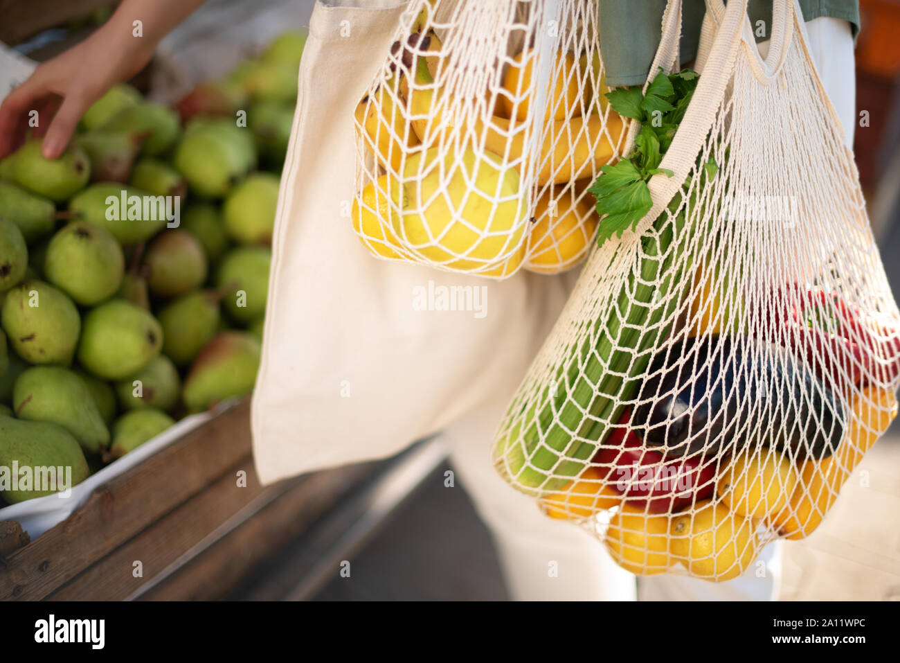Cero residuos, concepto libre de plástico. Estilo de vida sostenible. Mujer  elige frutas y verduras en el mercado de los granjeros. Y malla de algodón reutilizables  bolsas ecológicas para Fotografía de stock -