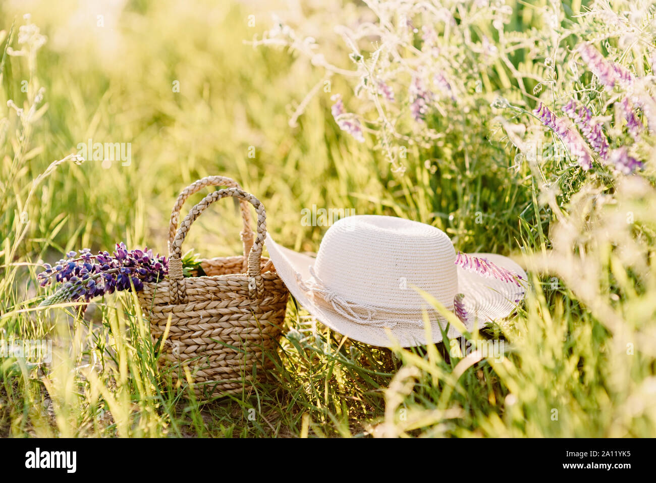 Romance rural. Un sombrero de trenzado y canasta de materiales naturales acostarse sobre la hierba Foto de stock