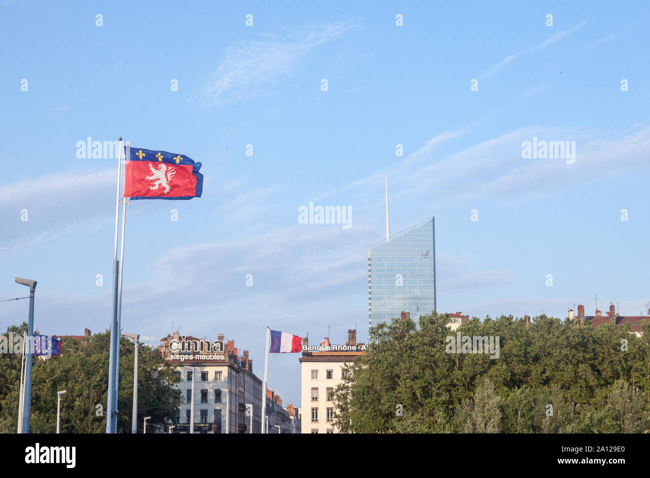 LYON, FRANCIA, 14 de julio de 2019: Bandera de Lyon renuncia delante del mostrador Incity Tower, un símbolo de la ciudad de negocios y los altos rascacielos de altura b Foto de stock