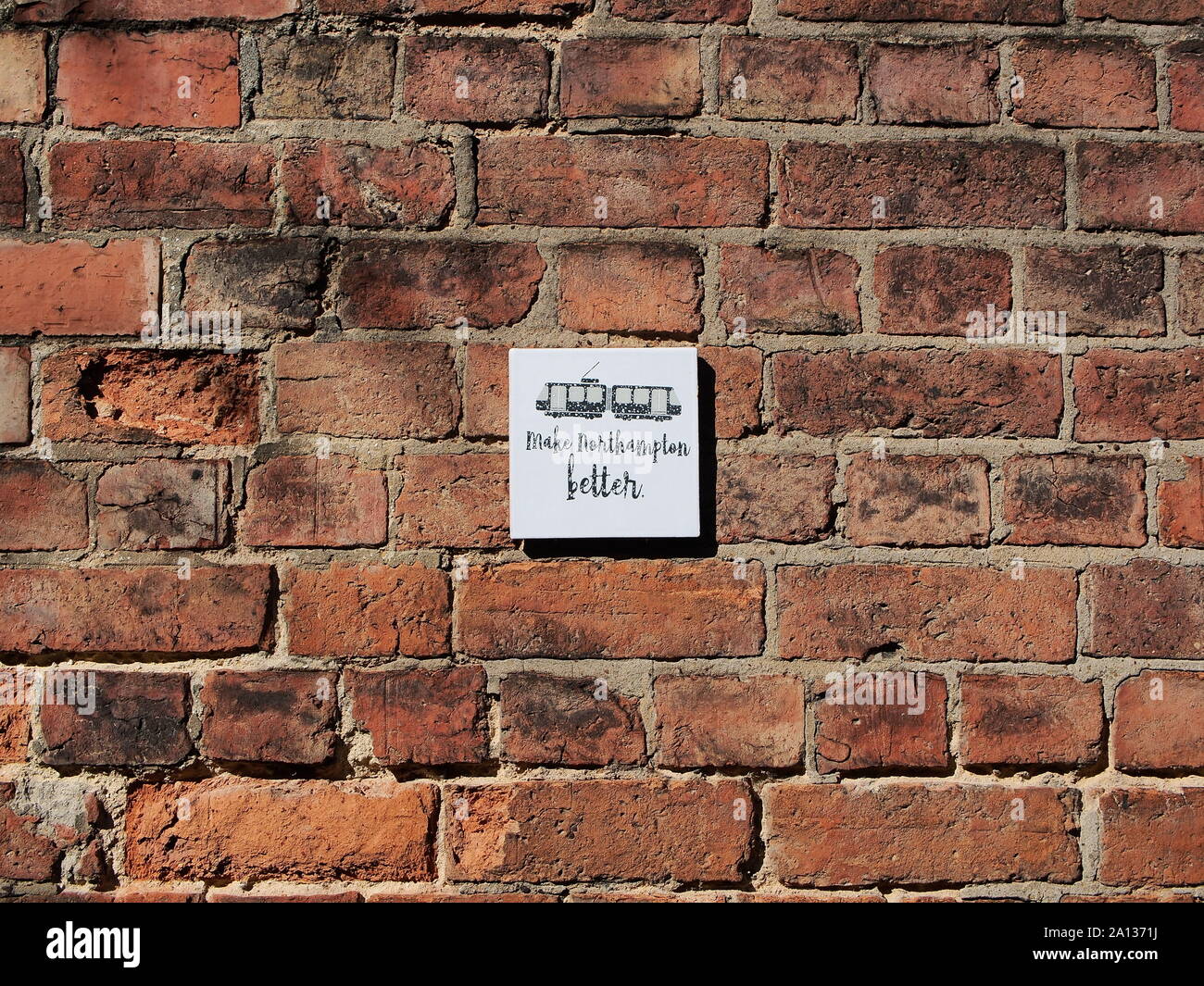 Hacer Northampton mejor firma fijado a una pared de ladrillo, Northampton, Reino Unido Foto de stock
