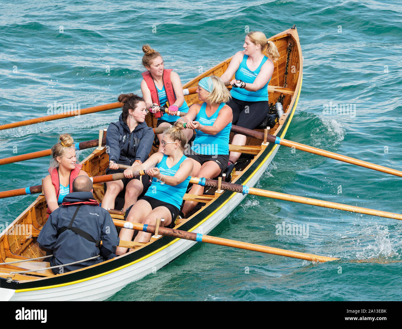 Las mujeres remo en equipos de seis en mano tradicional concierto experimental construido barcos. la tasa anual de West Country evento atrae a equipos de Europa (Londres Cornish) Foto de stock
