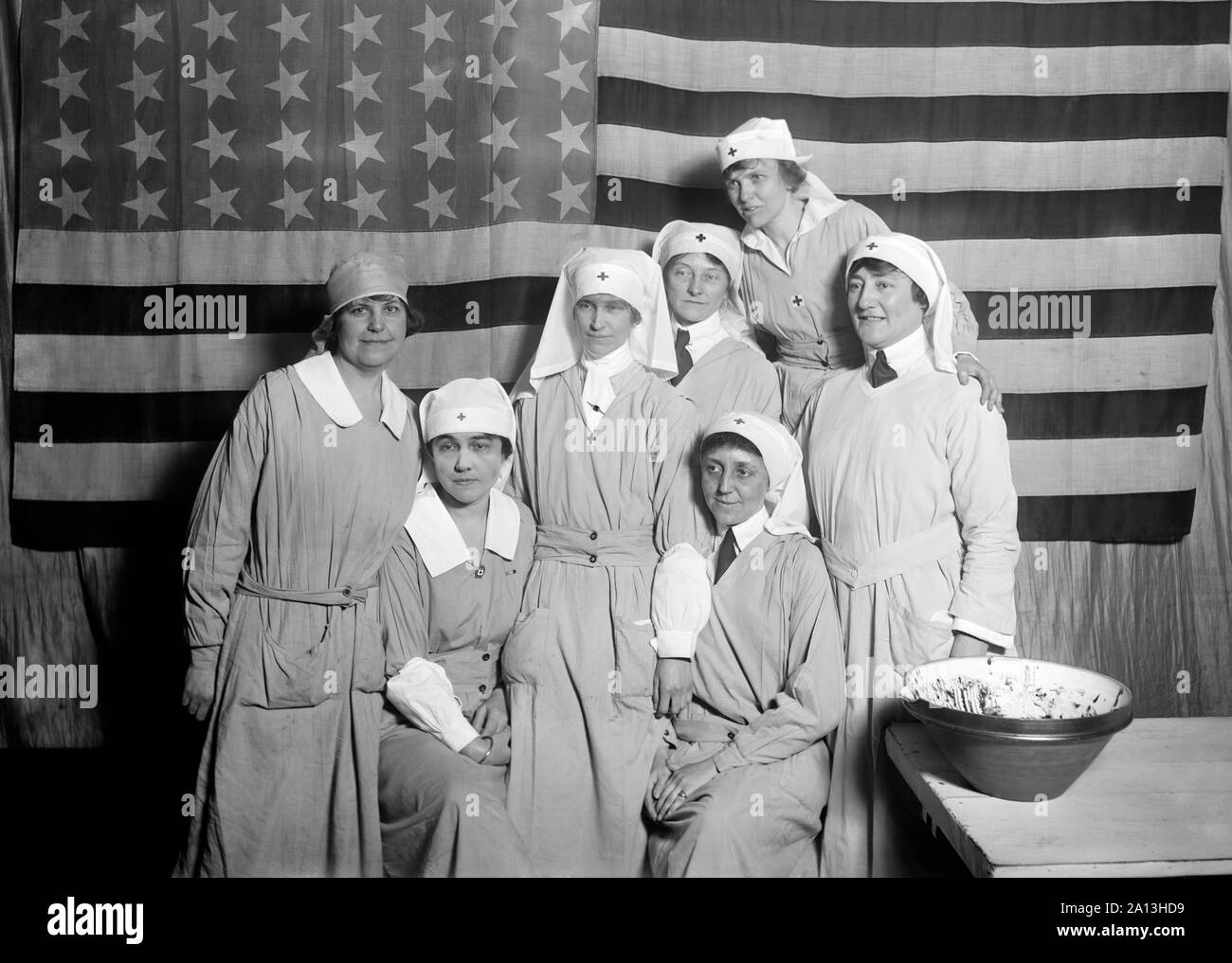 Un grupo de trabajadores de la Cruz Roja Americana de pie con la bandera americana, París, 1919. Foto de stock