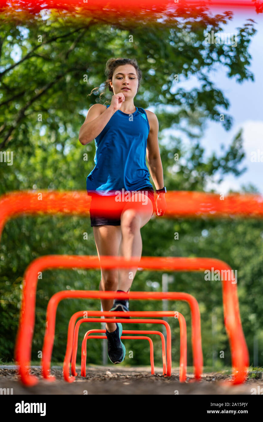 Mujer joven saltar por encima de obstáculos en un sendero de astillas de madera Foto de stock