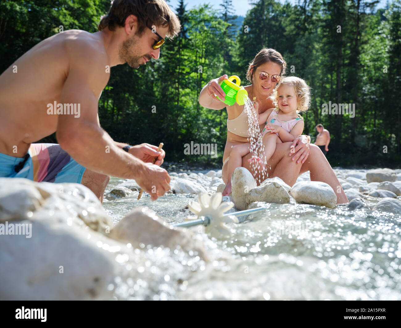 Familia con la hija de fijación rueda de agua en un arroyo de montaña Foto de stock