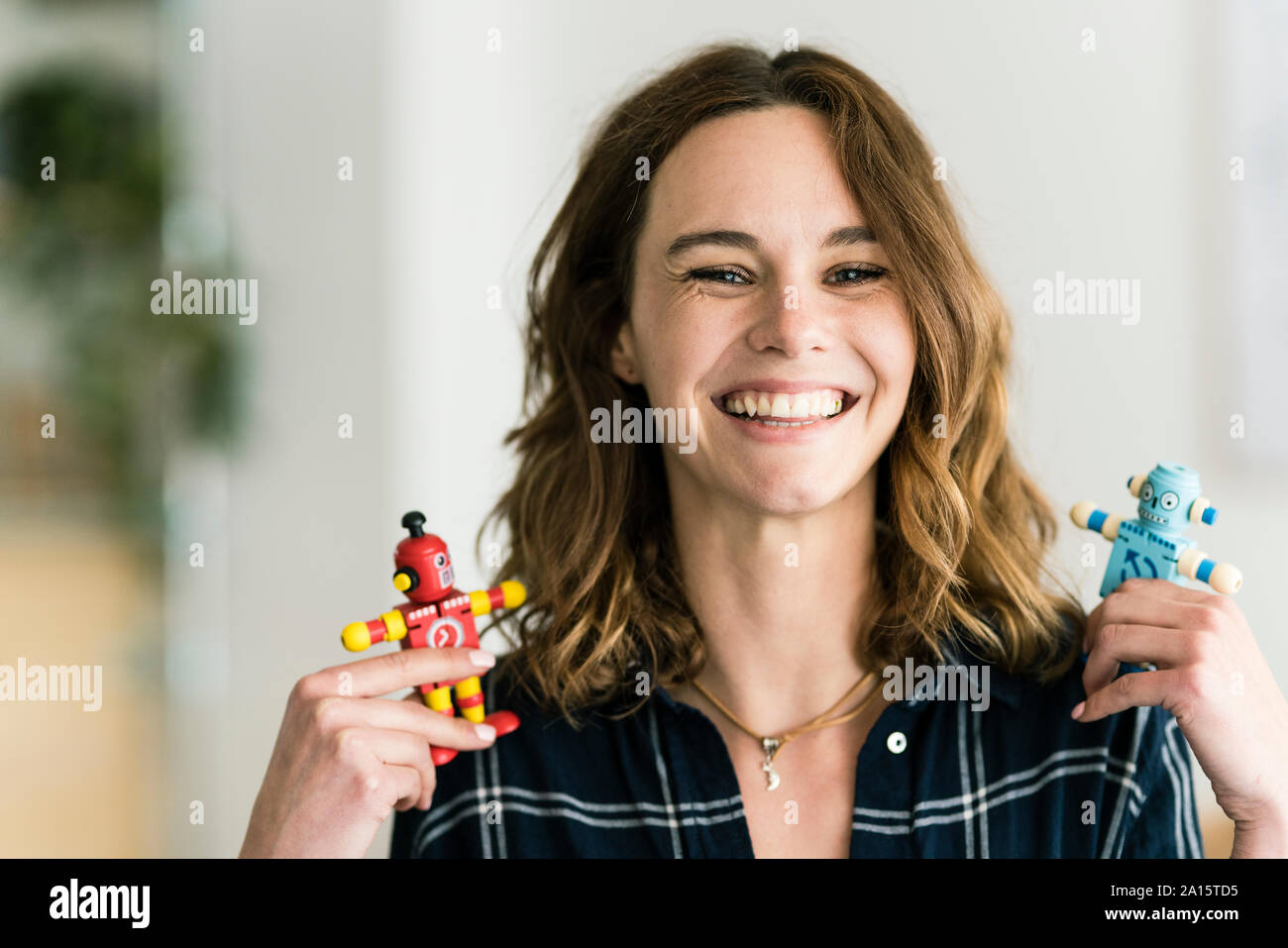 Mujer sosteniendo risa masculinos y femeninos de robots de juguete Foto de stock
