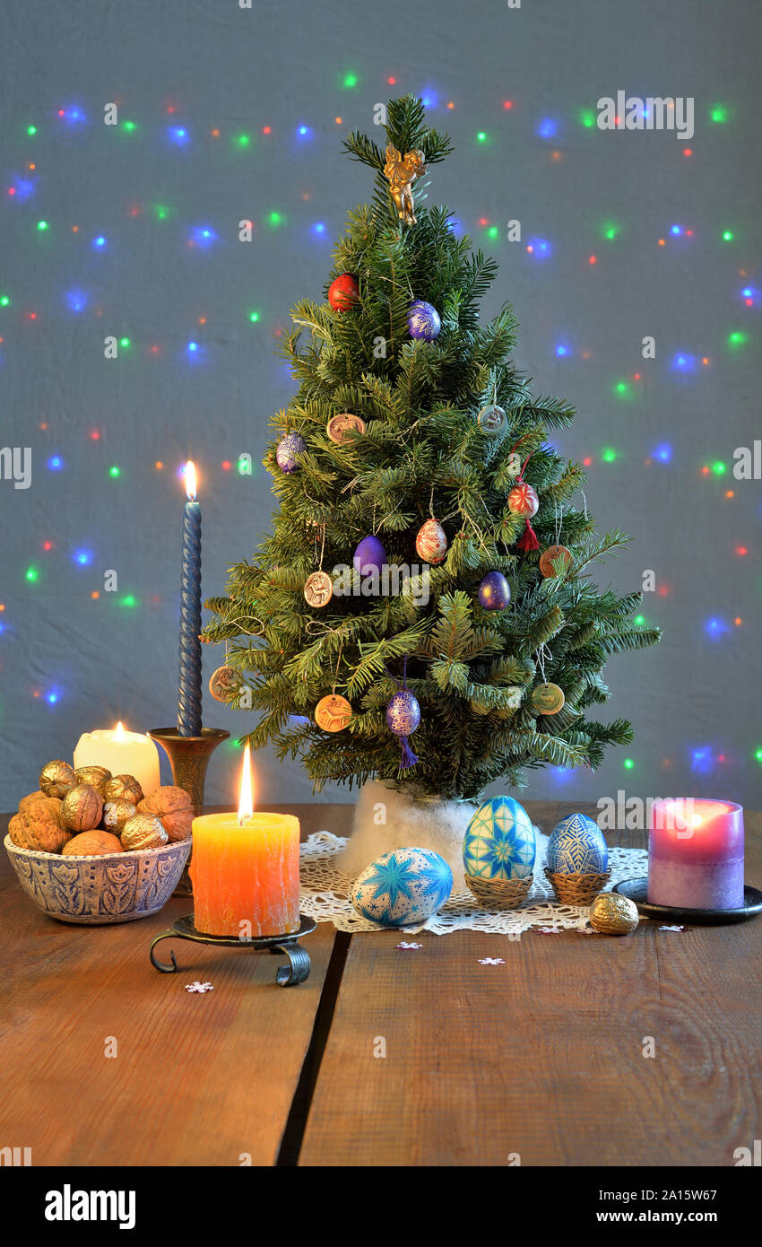 Árbol de Navidad rodeado de las velas, nueces, huevos pintados en la tabla Foto de stock