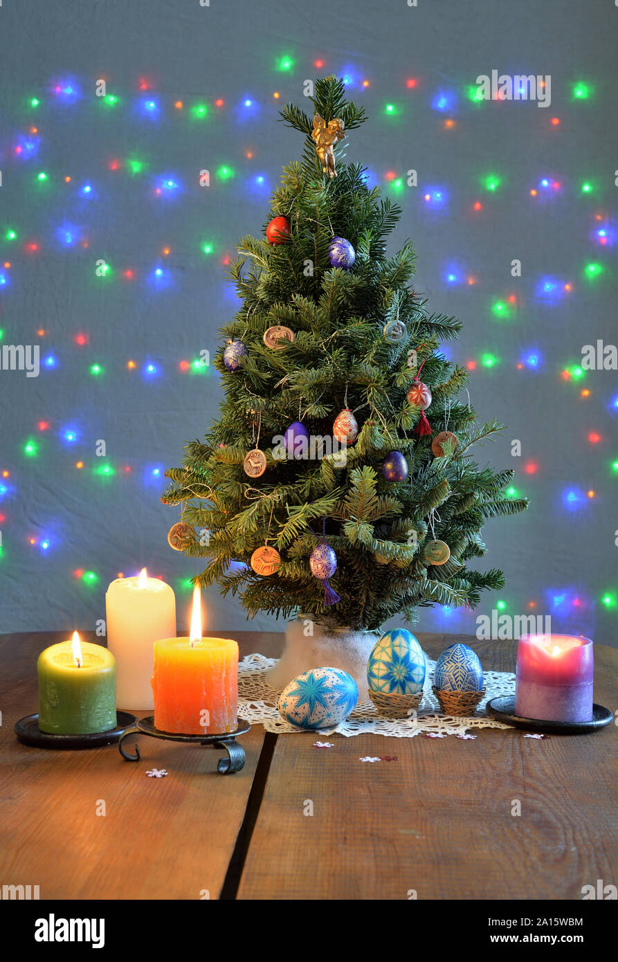Árbol de Navidad rodeado de las velas y los huevos coloreados en la mesa Foto de stock