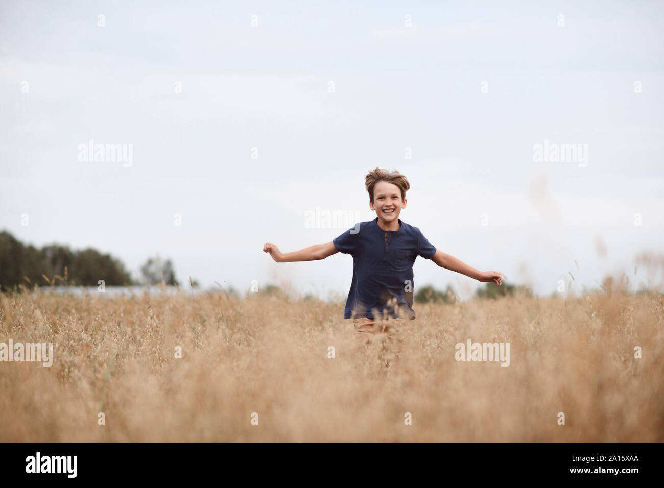 Retrato de risa niño corriendo en un campo de avena Foto de stock
