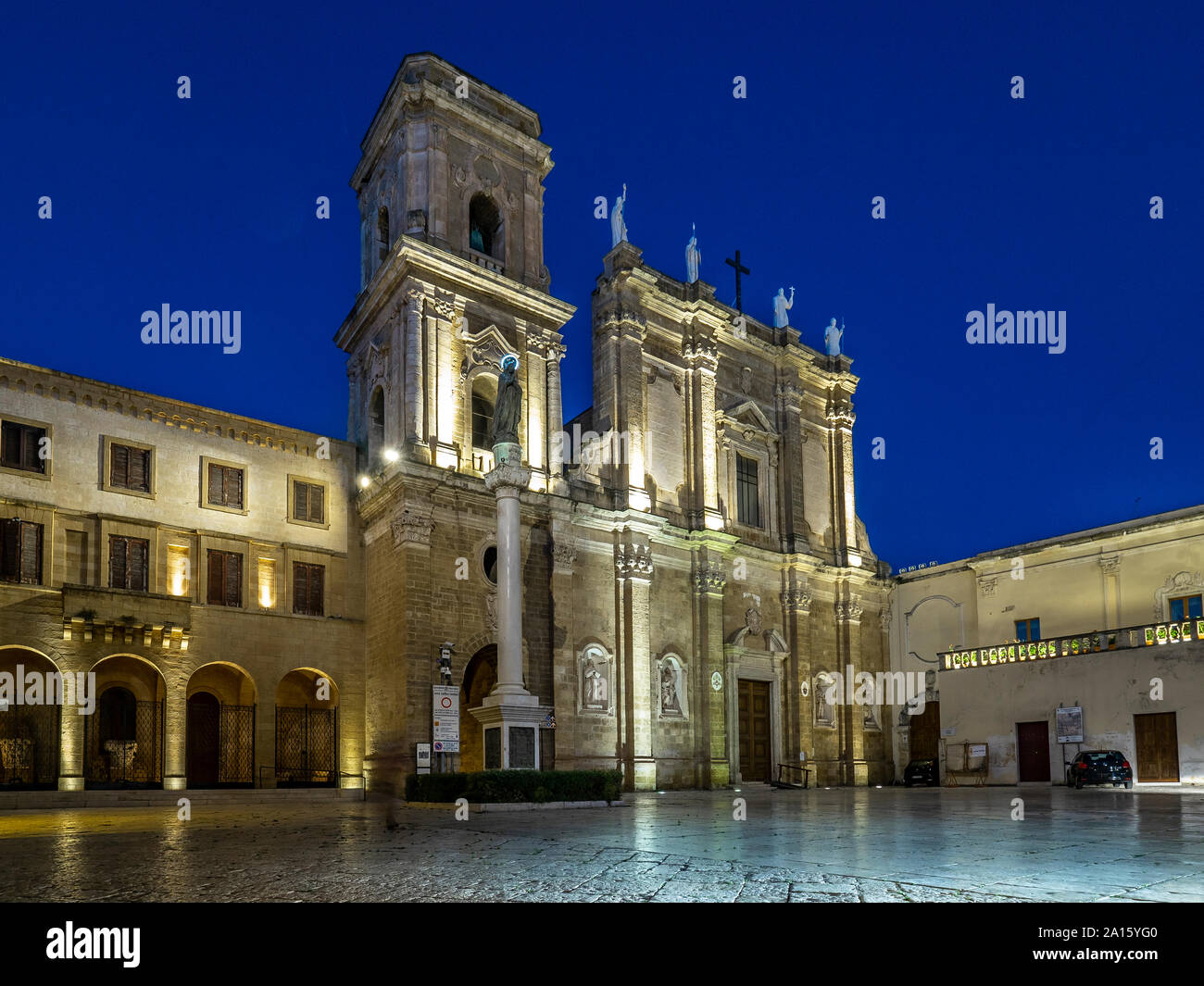 Fachada de la catedral iluminada en Brindisi contra el azul claro del cielo en la noche Foto de stock