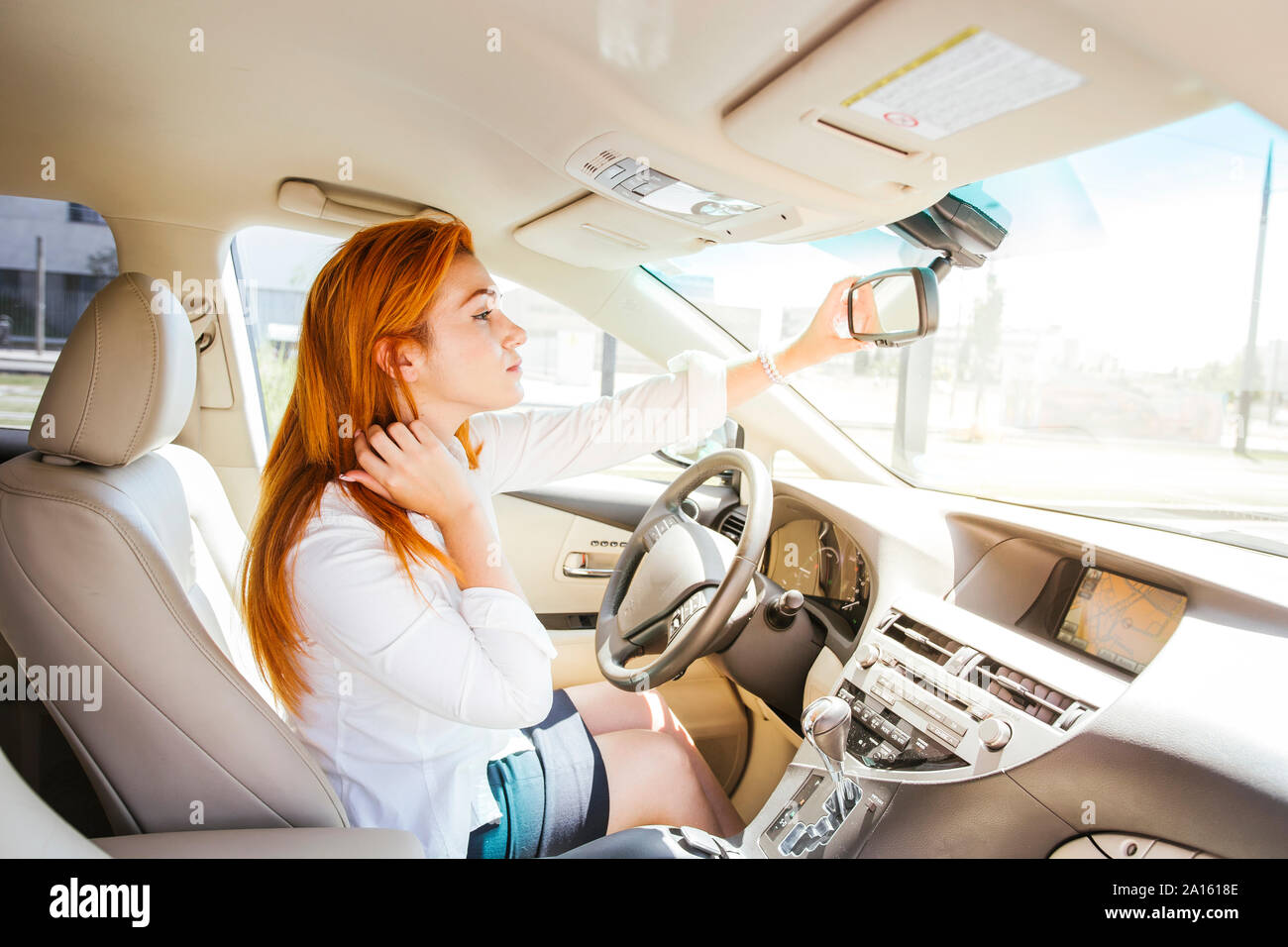 Mujer de negocios en un automóvil comprobando su mirada en el espejo retrovisor. Foto de stock