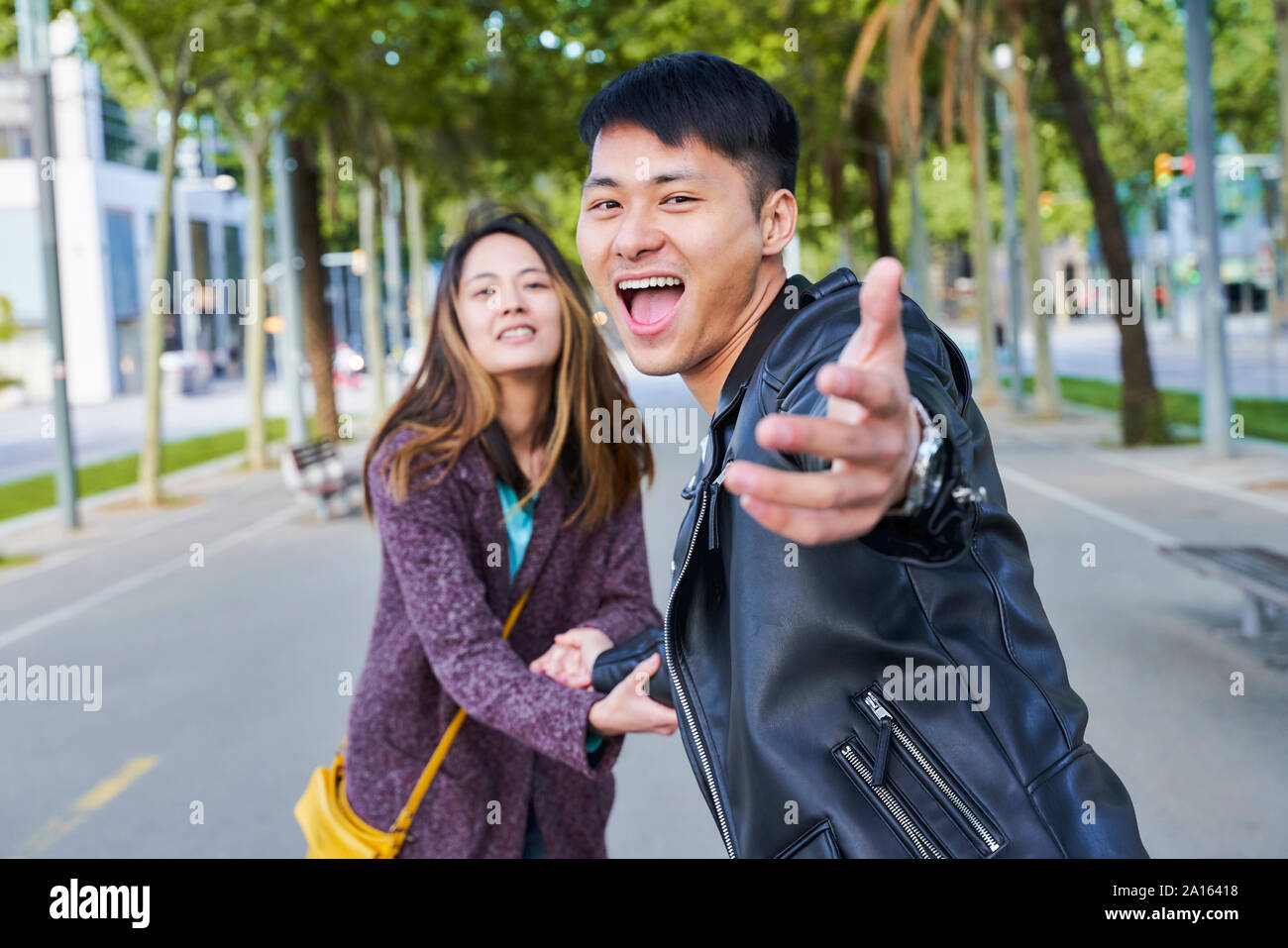 Feliz pareja invitar a alguien a unirse a ellos para una caminata, Barcelona, España Foto de stock