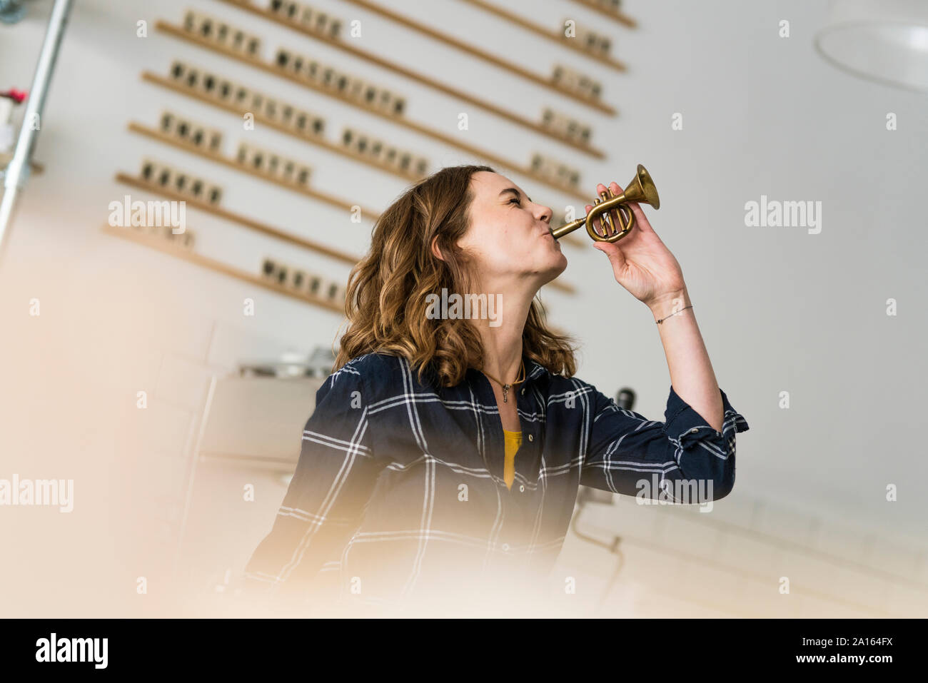 Mujer joven que sopla la trompeta de juguete en su cafetería Foto de stock