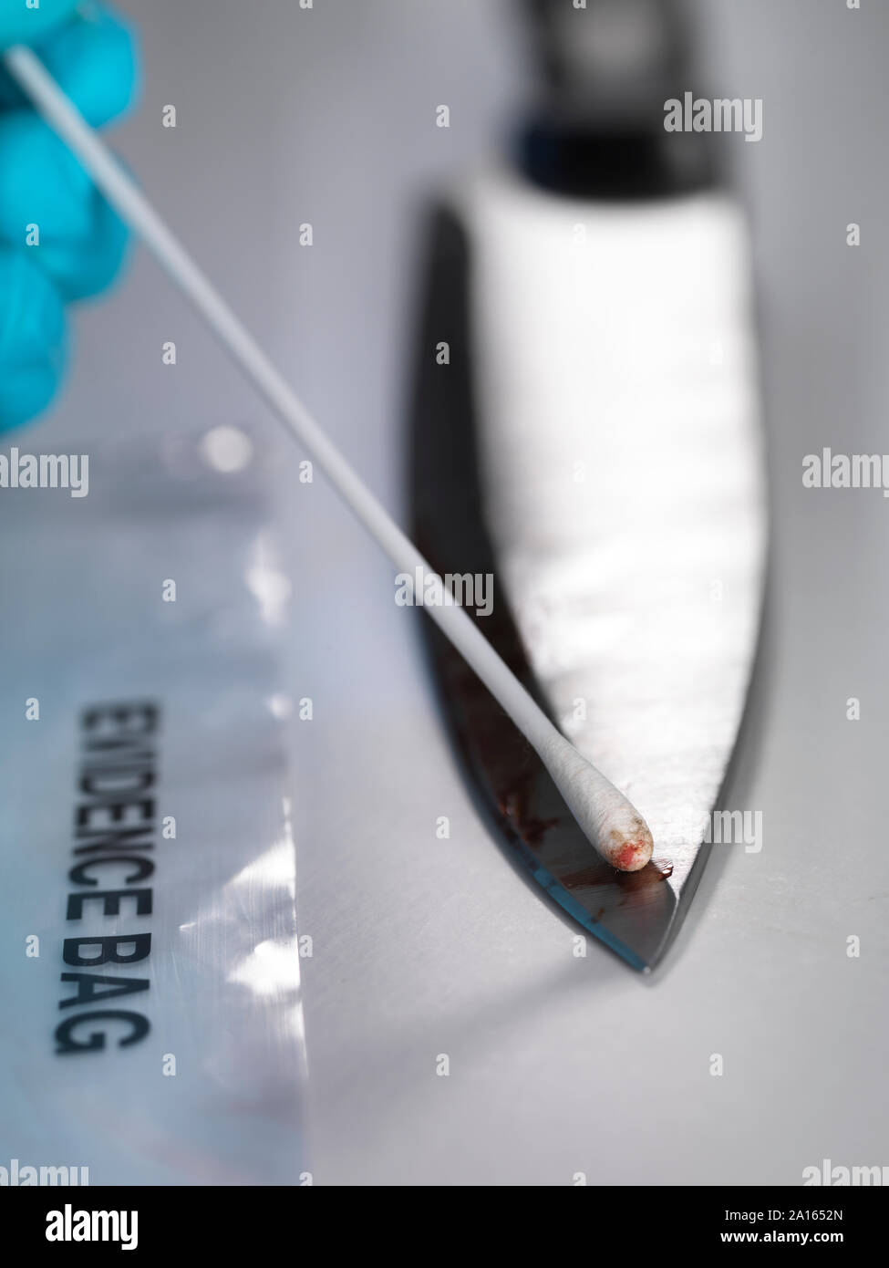 Científico Forense, tomando pruebas de ADN a partir de una navaja manchada de sangre Foto de stock