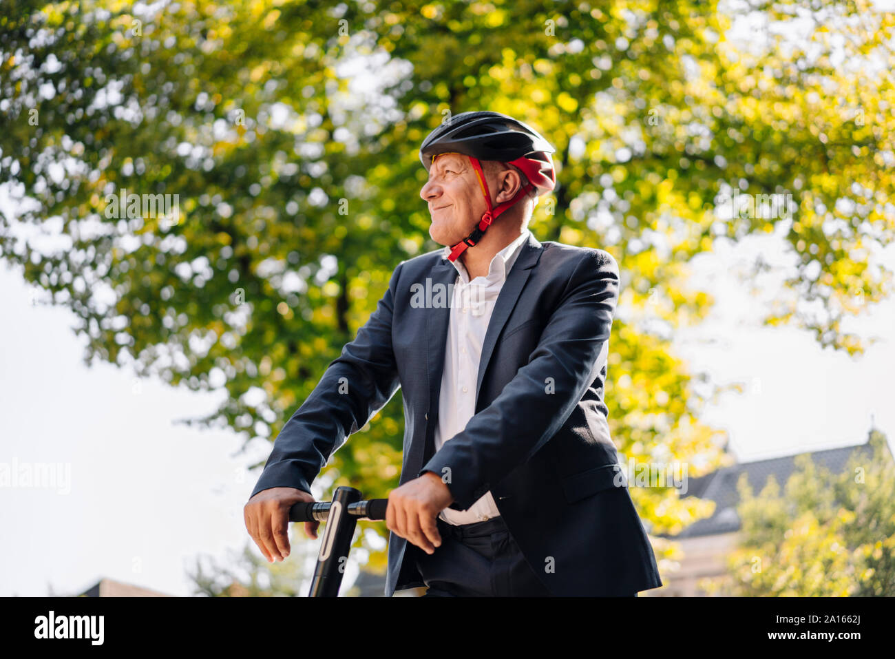 Retrato del hombre senior sonriente con e-scooter en la ciudad Foto de stock