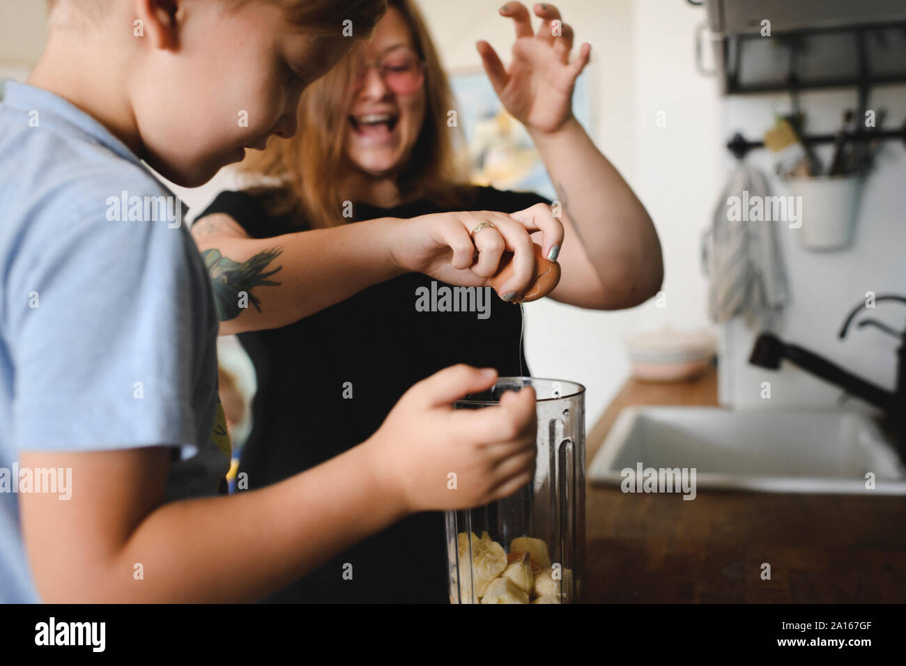 Madre e hijo cocinar panqueques de banana en cocina en casa Foto de stock