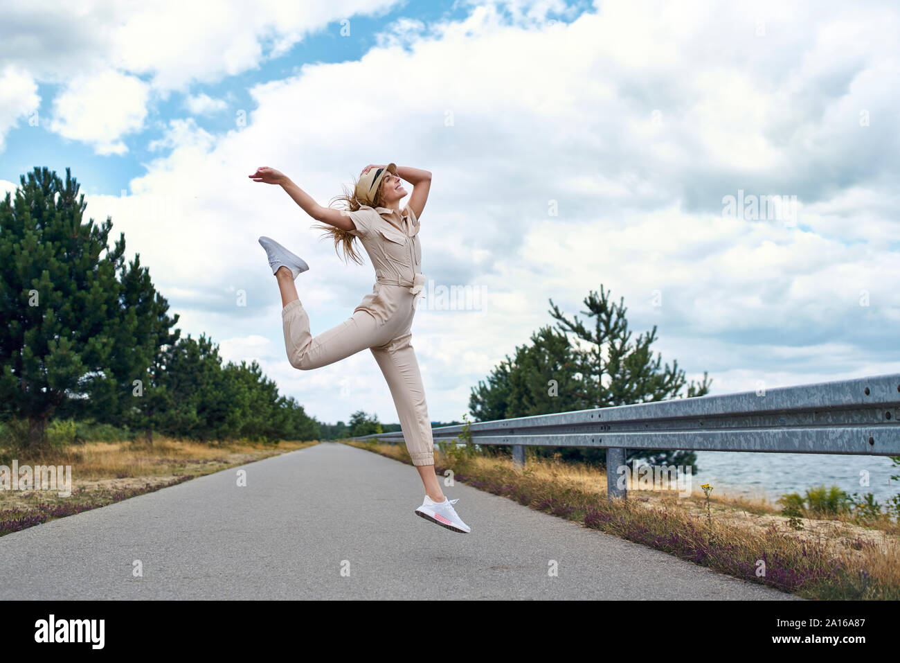 Mujer alegre saltando sobre carretera rural Foto de stock