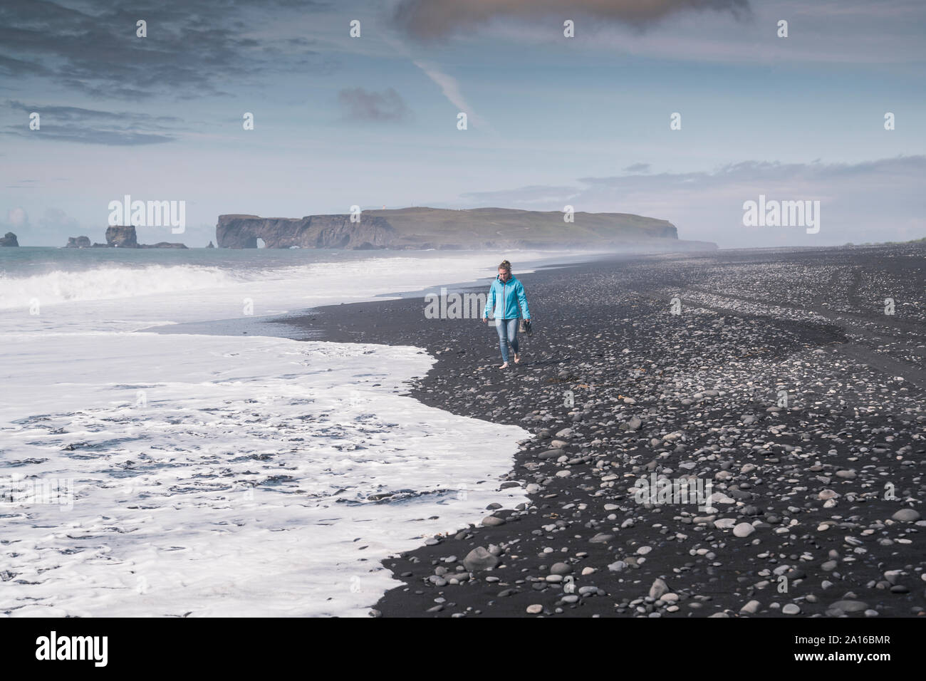 Mujer joven caminar descalzo en una playa de lava en Islandia Foto de stock