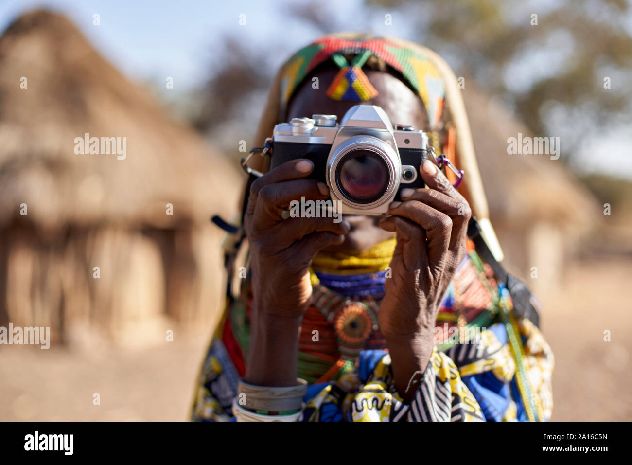 Mujer tradicional Muhila tomando fotos con una cámara, Kehamba, Chibia, Angola Foto de stock